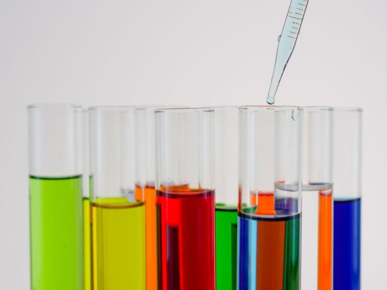 Rack of test tubes holding coloured liquids with a pipette above them
